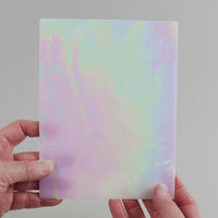 Video of the pearl glass plate in white translucent iridescent, 15x19cm, held up and tilted to show its pattern and transparency
