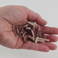 Video of Flip ceramic puzzle pieces in mocha, opaque glazed porcelain, 4–20 mm, held in a hand and poured out to show their shapes and finish