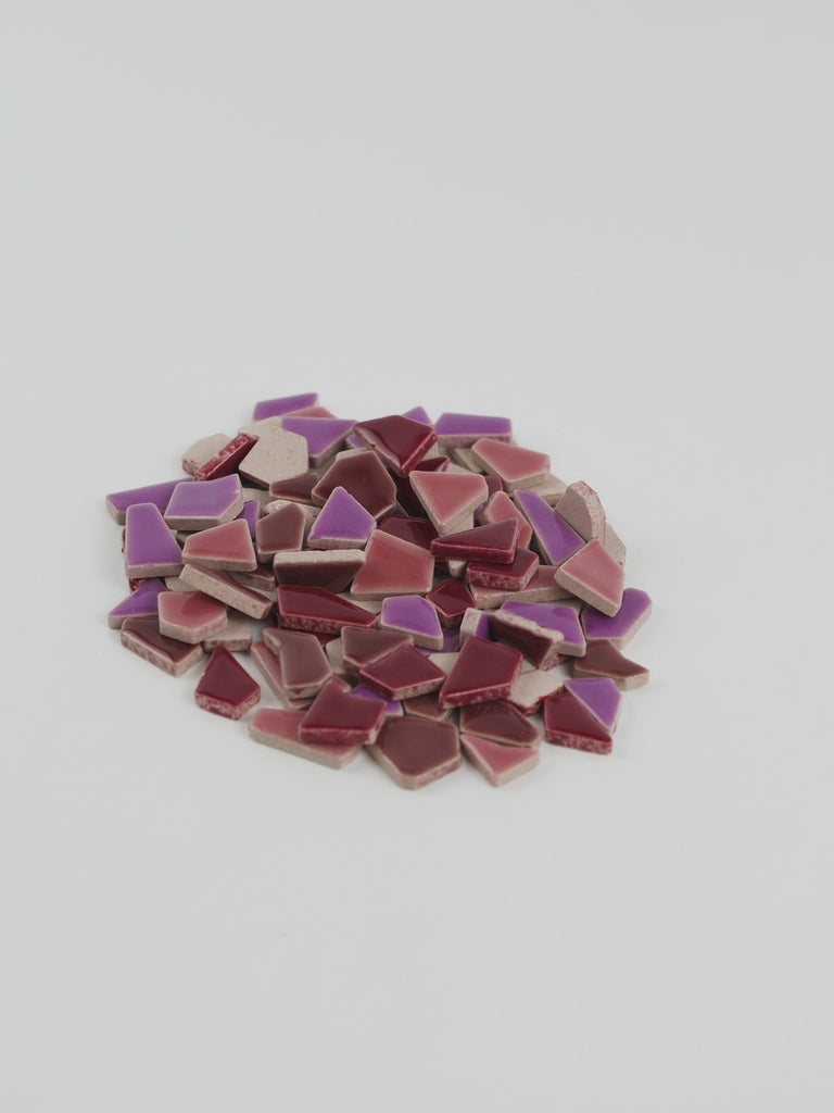 Video of Flip ceramic puzzle pieces in purple mix, opaque glazed porcelain, 4–20 mm, held in a hand and poured out to show their shapes and finish
