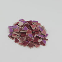 Video of Flip ceramic puzzle pieces in purple mix, opaque glazed porcelain, 4–20 mm, held in a hand and poured out to show their shapes and finish