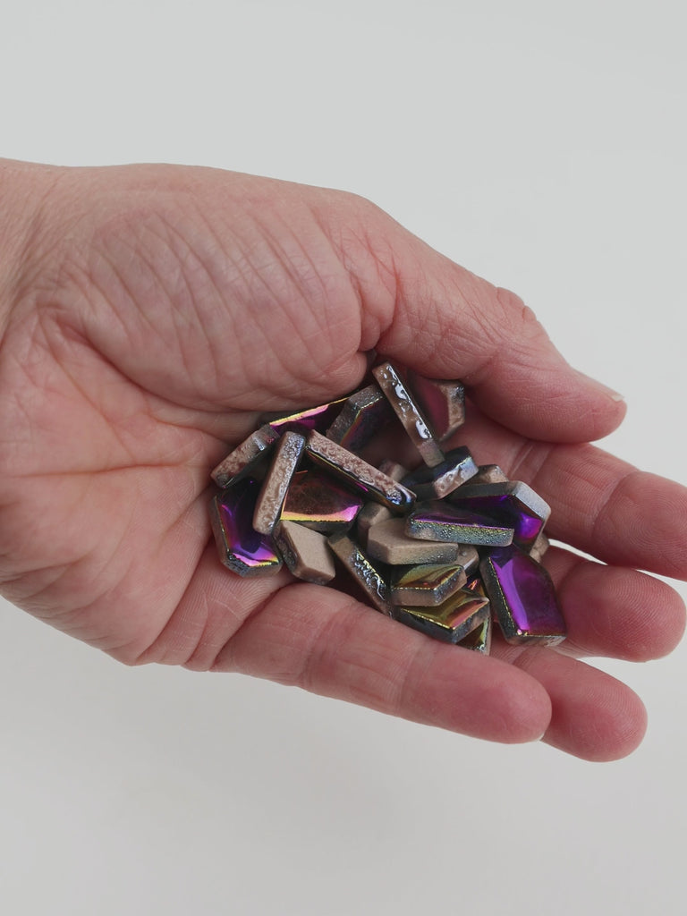 Video of Flip ceramic puzzle pieces in rainbow colors, opaque glazed porcelain, 4–20 mm, held in a hand and poured out to show their shapes and finish