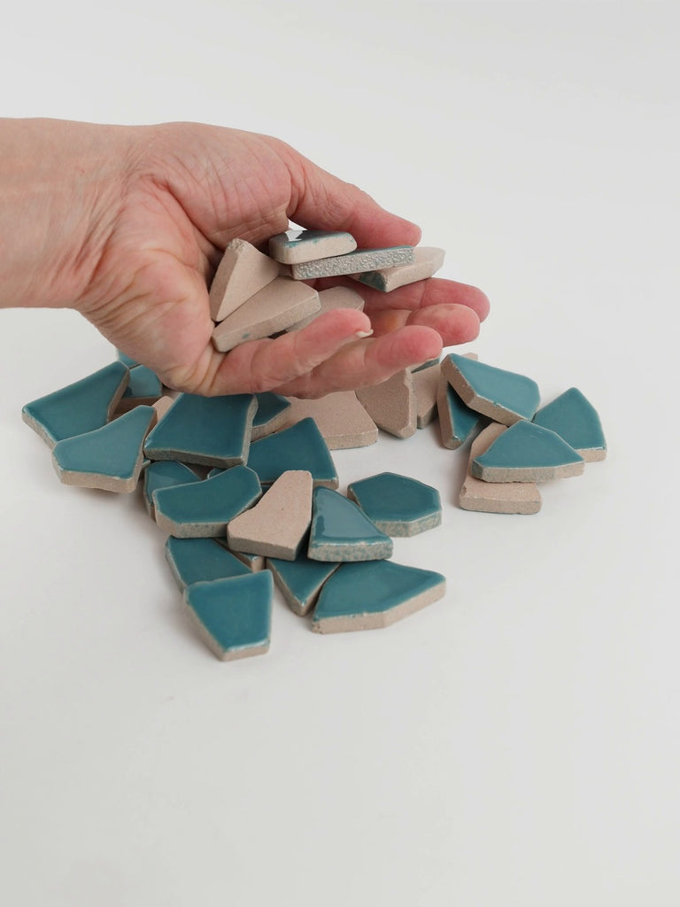 Video of Flip XL ceramic puzzle pieces in mint green, opaque glazed porcelain, 20–60 mm, picked up from a pile by hand and dropped back to show their size, shapes and finish