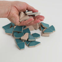 Video of Flip XL ceramic puzzle pieces in mint green, opaque glazed porcelain, 20–60 mm, picked up from a pile by hand and dropped back to show their size, shapes and finish