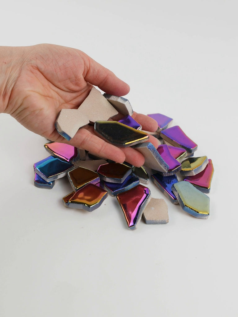 Video of Flip XL ceramic puzzle pieces in rainbow colors, opaque glazed porcelain, 20–60 mm, picked up from a pile by hand and dropped back to show their size, shapes and finish