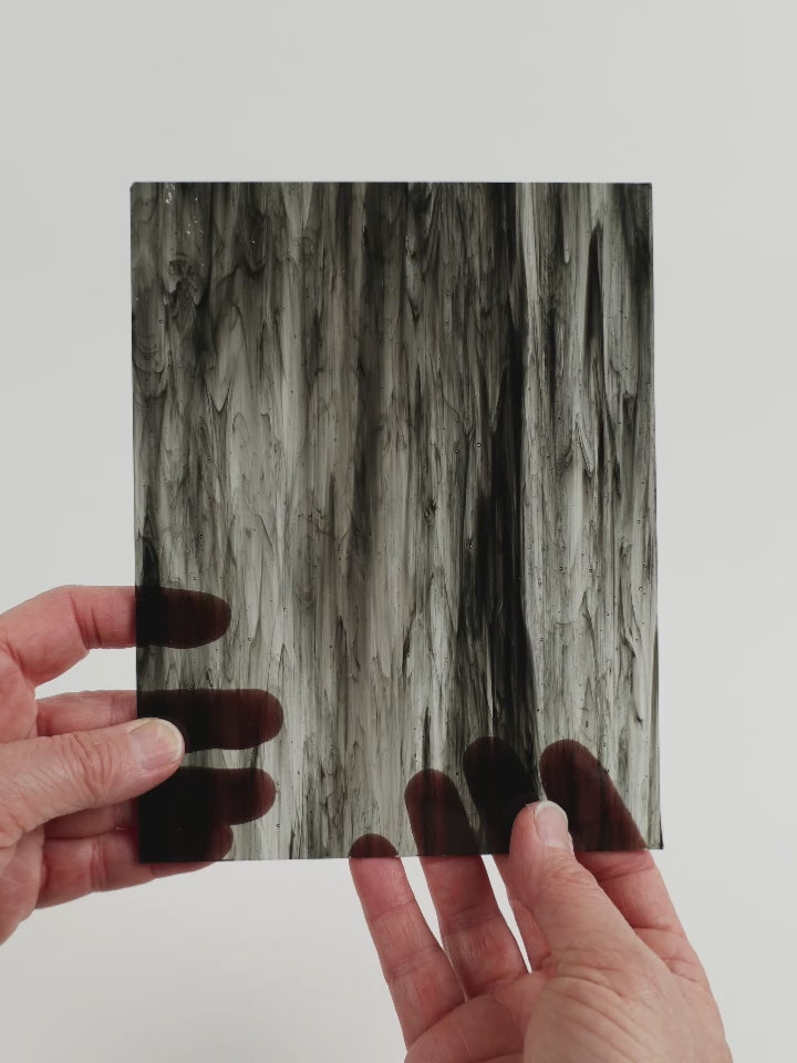Video of the Marble Magic glass plate in black, transparent and marbled finish, 15x19cm, held up and tilted to show its pattern and transparency.