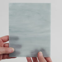 Video of the grey smoke glass plate in grey translucent marbled, 15x19cm, held up and tilted to show its pattern and transparency