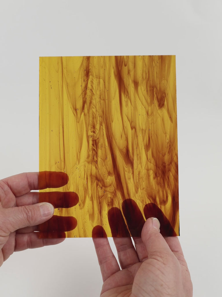 Video of the Mid Brown Wispy glass plate in transparant brown, 15x19cm, held up and tilted to show its pattern and transparency