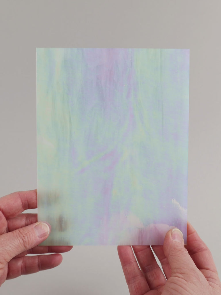 Video of the white iridescent wispy glass plate in semi-transparant white , 15x19cm, held up and tilted to show its pattern and transparency